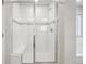 Modern walk-in shower features white tiles, a glass door, and a built-in bench at 594 Fall River Ct, Brighton, CO 80601