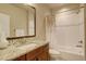 Bright bathroom features a granite topped vanity with a dark-stained cabinets and framed mirror, plus tub shower combo at 9441 Night Star Pl, Lone Tree, CO 80124