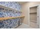 Bright laundry room featuring patterned wallpaper, shelving, and a wood countertop for folding clothes at 3844 Sandy Vista Ln, Castle Rock, CO 80104