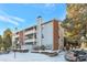Apartment building featuring updated exterior with brick accents, private balconies, and landscaped grounds in winter at 14208 E 1St Dr # C1, Aurora, CO 80011