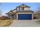 Two-story tan home with a blue two-car garage, light stone accents, and a covered porch at 11642 Moline Ct, Commerce City, CO 80640