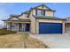 Two-story tan home with a blue two-car garage, light stone accents, and a covered porch at 11642 Moline Ct, Commerce City, CO 80640