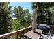 Back deck with a patio table and umbrella surrounded by lush trees and a grill at 11526 Green Cir, Conifer, CO 80433