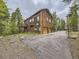Stunning multi-story cabin featuring a spacious driveway, deck, and attached two-car garage at 11526 Green Cir, Conifer, CO 80433