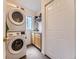 A conveniently stacked washer and dryer sit beside a utility sink, with extra storage cabinets above in this laundry room at 11526 Green Cir, Conifer, CO 80433