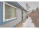 Exterior view of a house with gray siding, blue trim, covered in light snow, and a security door at 2504 S Victor St # E, Aurora, CO 80014