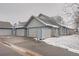 Exterior view of a three-car garage with gray siding, blue trim, and driveway covered with snow at 2504 S Victor St # E, Aurora, CO 80014