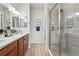 Well-lit bathroom with double vanity, wood cabinets, and a modern glass-enclosed shower at 4063 Castle Vista Dr, Castle Rock, CO 80104