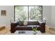 Living room with a leather couch and a large window overlooking mature trees at 5516 S Havana Ct, Englewood, CO 80111