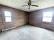 Empty bedroom showcasing wood walls, flooring in need of repair, ceiling fan, and natural light from the windows at 11897 Roxburg St, Strasburg, CO 80136