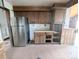 Kitchen area with modern stainless steel refrigerator and classic wooden cabinets at 11897 Roxburg St, Strasburg, CO 80136