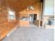 Open-concept living room with wood walls, tile flooring, and a glimpse into the kitchen and fireplace at 11897 Roxburg St, Strasburg, CO 80136