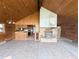 Open-concept living room highlighting tile flooring, a stone fireplace, wood walls, and seamless connection to the kitchen area at 11897 Roxburg St, Strasburg, CO 80136