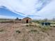 A distant shed structure with a few trash cans, with lots of open space at 11897 Roxburg St, Strasburg, CO 80136