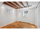 Finished basement area with laminate flooring, exposed ceiling beams, and natural light from two windows at 424 S Pennsylvania St, Denver, CO 80209