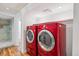 Bright laundry room with modern red washer and dryer, tile floors, and a glass door to the shower room at 424 S Pennsylvania St, Denver, CO 80209