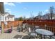 Back deck includes a dining area, seating area, wooden railings, and houses in background at 20500 E Hamilton Ave, Aurora, CO 80013