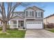 Charming two-story home with a well-maintained lawn, gray siding, white trim, covered porch, and attached two-car garage at 9879 Sydney Ln, Highlands Ranch, CO 80130