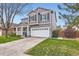A beautiful two-story home showcasing a well-manicured lawn and a covered front porch with a two-car garage at 9879 Sydney Ln, Highlands Ranch, CO 80130