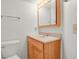 Bathroom featuring a wood vanity, updated lighting, sink, toilet, and fixtures at 17034 E Tennessee Dr # 106, Aurora, CO 80017