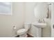 Charming half bathroom with pedestal sink, round mirror, toilet, and window providing natural light at 2682 E 161St Pl, Thornton, CO 80602