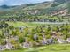 Picturesque aerial view of a golf course community with mountain views and a lake at 15851 Deer Ridge Dr, Morrison, CO 80465