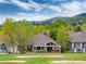 Scenic backyard featuring a covered patio, a hot tub, green lawns, and mature trees near a golf course at 15851 Deer Ridge Dr, Morrison, CO 80465