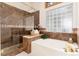 Main bath featuring a luxurious tub, glass enclosed shower, and tile surround at 15851 Deer Ridge Dr, Morrison, CO 80465