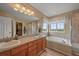 Bright bathroom featuring a dual sink vanity, soaking tub, a separate shower, and a walk-in closet at 1120 N Calhan Ave, Castle Rock, CO 80104