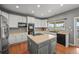 Well-lit kitchen featuring a central island, stainless steel appliances, white cabinets, and hardwood floors at 1120 N Calhan Ave, Castle Rock, CO 80104