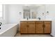 Bathroom featuring a double sink vanity with wood cabinets and a modern white bathtub at 39730 Congress Ln, Elizabeth, CO 80107