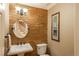 Stylish powder room featuring stacked stone accent wall, pedestal sink, and a round decorative mirror at 7169 S Grape Ln, Centennial, CO 80122