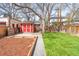 Spacious backyard featuring a storage shed, garden beds, lush green lawn, mature trees, and privacy fencing at 2235 S Fillmore St, Denver, CO 80210