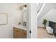 Stylish half bath with modern vanity and mirror adjacent to open staircase at 5569 Willow Springs Dr, Morrison, CO 80465