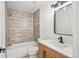 Bright, updated bathroom with modern fixtures, a tiled shower-tub combo, and stylish wood vanity at 5569 Willow Springs Dr, Morrison, CO 80465