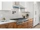 Gourmet kitchen featuring stainless steel appliances, a modern range hood, and white subway tile at 5569 Willow Springs Dr, Morrison, CO 80465