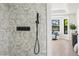 A bathroom shower with geometric tile, black hardware, and a view to the bedroom at 5569 Willow Springs Dr, Morrison, CO 80465