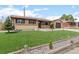 Charming single-story house with a lush green lawn, brick accents, and a detached garage in a suburban setting at 7961 Granada Rd, Denver, CO 80221