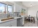 Modern white kitchen features stainless steel appliances and a charming breakfast nook at 7961 Granada Rd, Denver, CO 80221