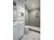 Modern bathroom with a glass shower, blue and white striped walls, white vanity, and herringbone tile floor at 2409 S Fillmore St, Denver, CO 80210