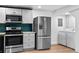 Modern kitchen features stainless steel appliances and a stylish teal backsplash, plus a washer and dryer at 3220 W 8Th Ave, Denver, CO 80204