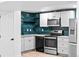 Beautifully updated kitchen features stainless steel appliances and eye-catching teal backsplash, with modern style at 3220 W 8Th Ave, Denver, CO 80204