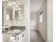 Bright bathroom with toilet, granite countertop, faucet, mirror and view into another room with a window at 3235 S Newland St, Denver, CO 80227