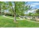 Community playground and pool area with a lush green lawn, mature trees, and ample recreational space at 7295 S Steele Cir, Centennial, CO 80122