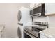 White kitchen including stackable washer/dryer, microwave, and stainless steel oven at 3041 S Glencoe St, Denver, CO 80222