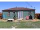 A cozy backyard featuring a small patio, garden, and a charming green house with a red roof and a sliding glass door at 1730 W 51St Ave, Denver, CO 80221