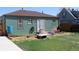 A cozy backyard featuring a small patio, garden, and a charming green house with a red roof and a sliding glass door at 1730 W 51St Ave, Denver, CO 80221