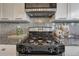 Close up on stainless gas range with granite counters and white cabinets at 3689 Primrose Ln, Castle Rock, CO 80109