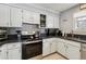 Well-lit kitchen featuring white cabinets, black countertops, and stainless steel appliances at 10474 W Purgatoire Peak, Littleton, CO 80127