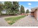 Spacious backyard features a grass area, gravel landscaping, mature trees, a patio set, and a red shed at 10525 W 18Th Ave, Lakewood, CO 80215